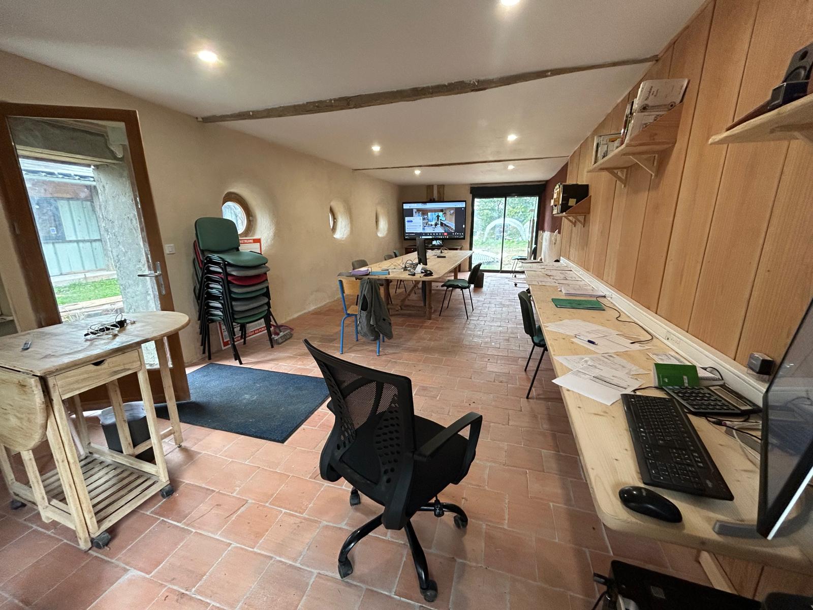 Les bureaux partagés de Chabaud : salle lumineuse au sol en terre cuite, postes de travail et table de réunion